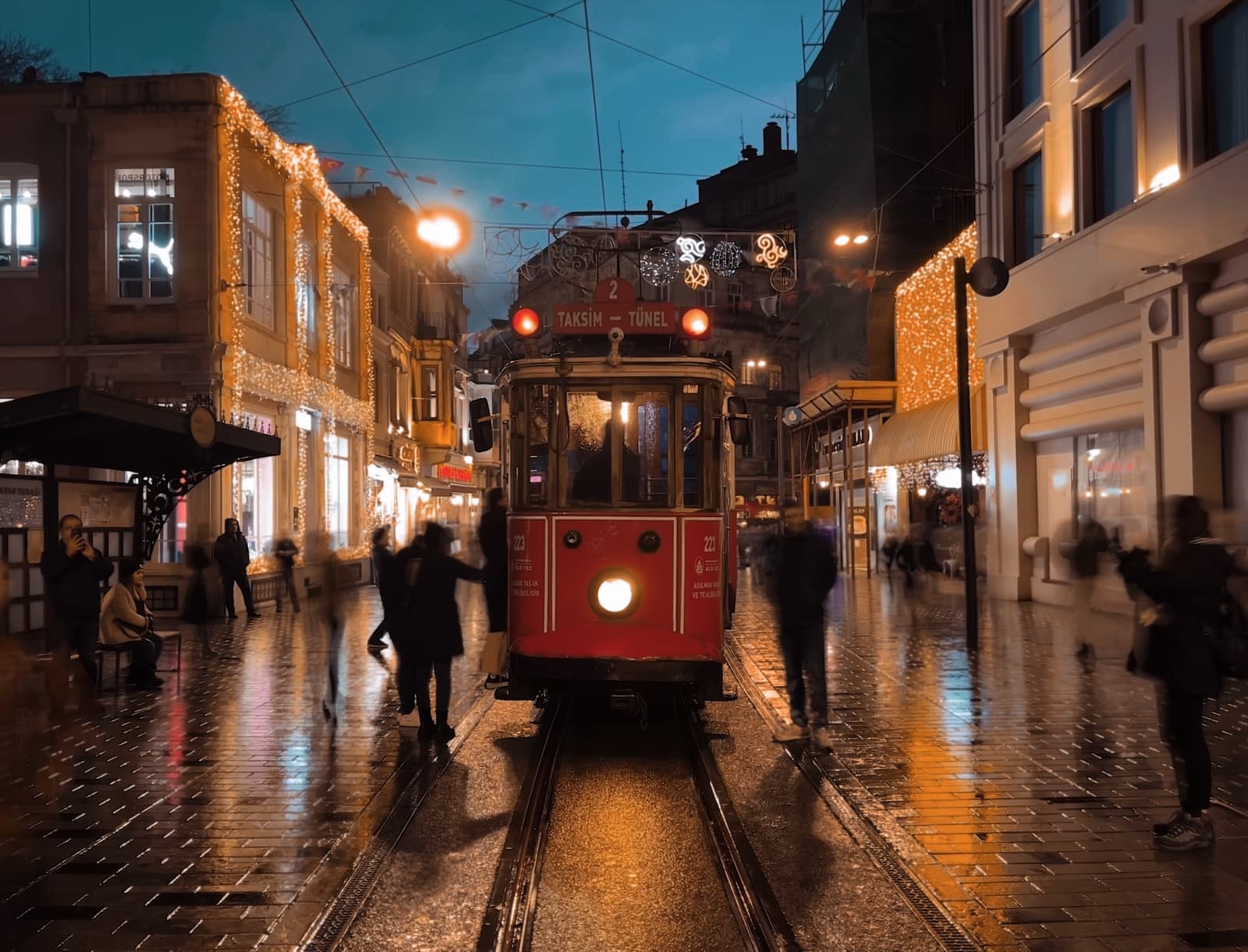 Red nostalgic tram on Istiklal Street in Istanbul on a rainy evening with lit shopfronts